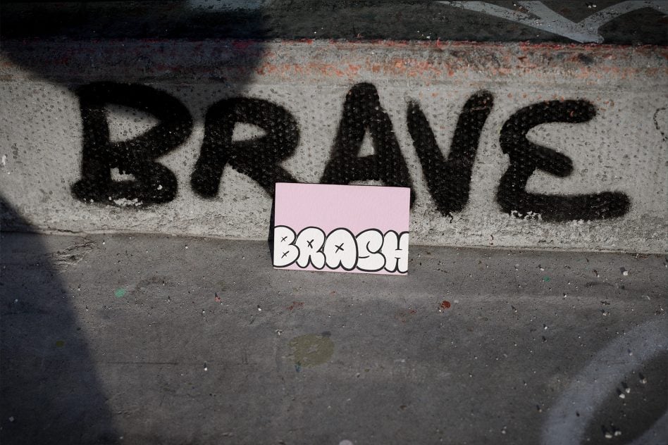 Pink business card mockup with doodle lettering overlaid on graffiti brick wall